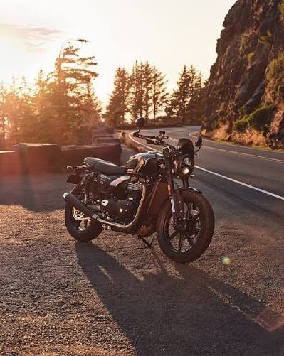 Triumph motorcycle on scenic Ozark mountain road at sunset
