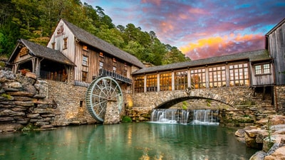 Historic grist mill with waterwheel beside turquoise stream at Dogwood Canyon